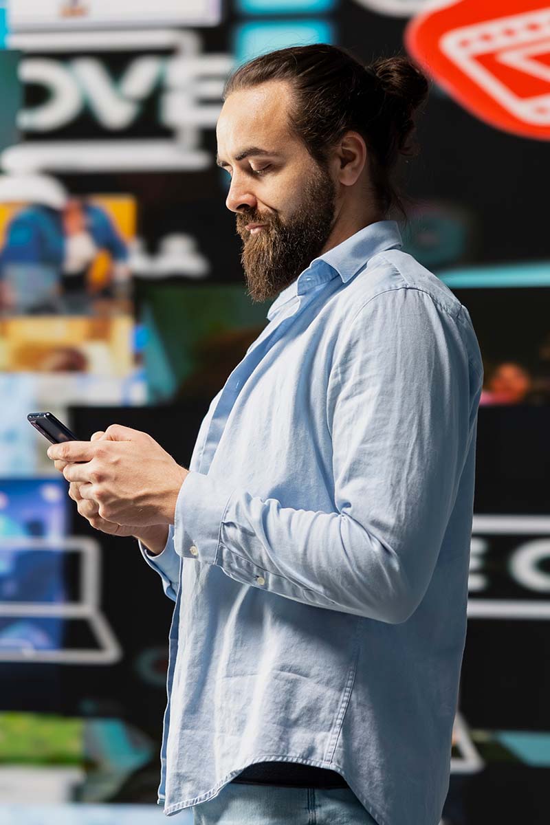 Caoches header 800x1200px bearded man on stage looking at mobile phone