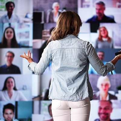 Live Events mobile 400x400px Lady standing presenting in front of a mulitiple screen of attendess