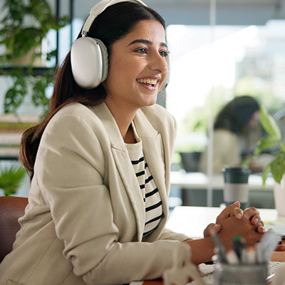 Live events onboarding mobile 400x400px Young professional female dressed in corporate attire with headphones on at desk watching and listening to an online employee induction event