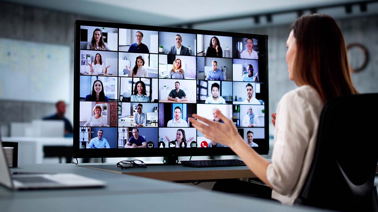 Short Courses 1280x720px Professional female sitting at desk looking to and talking with a group of people from various countires in the world
