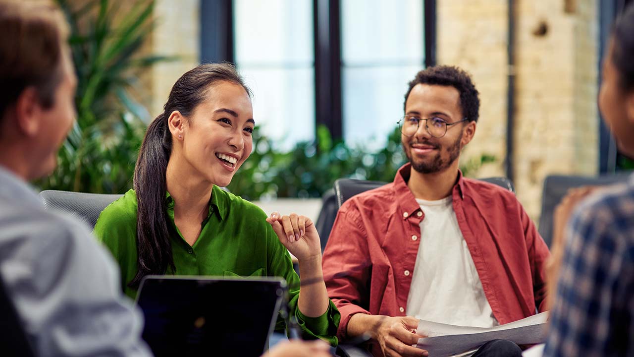Group of workplace graduates sitting in a common area discussing a work scenario